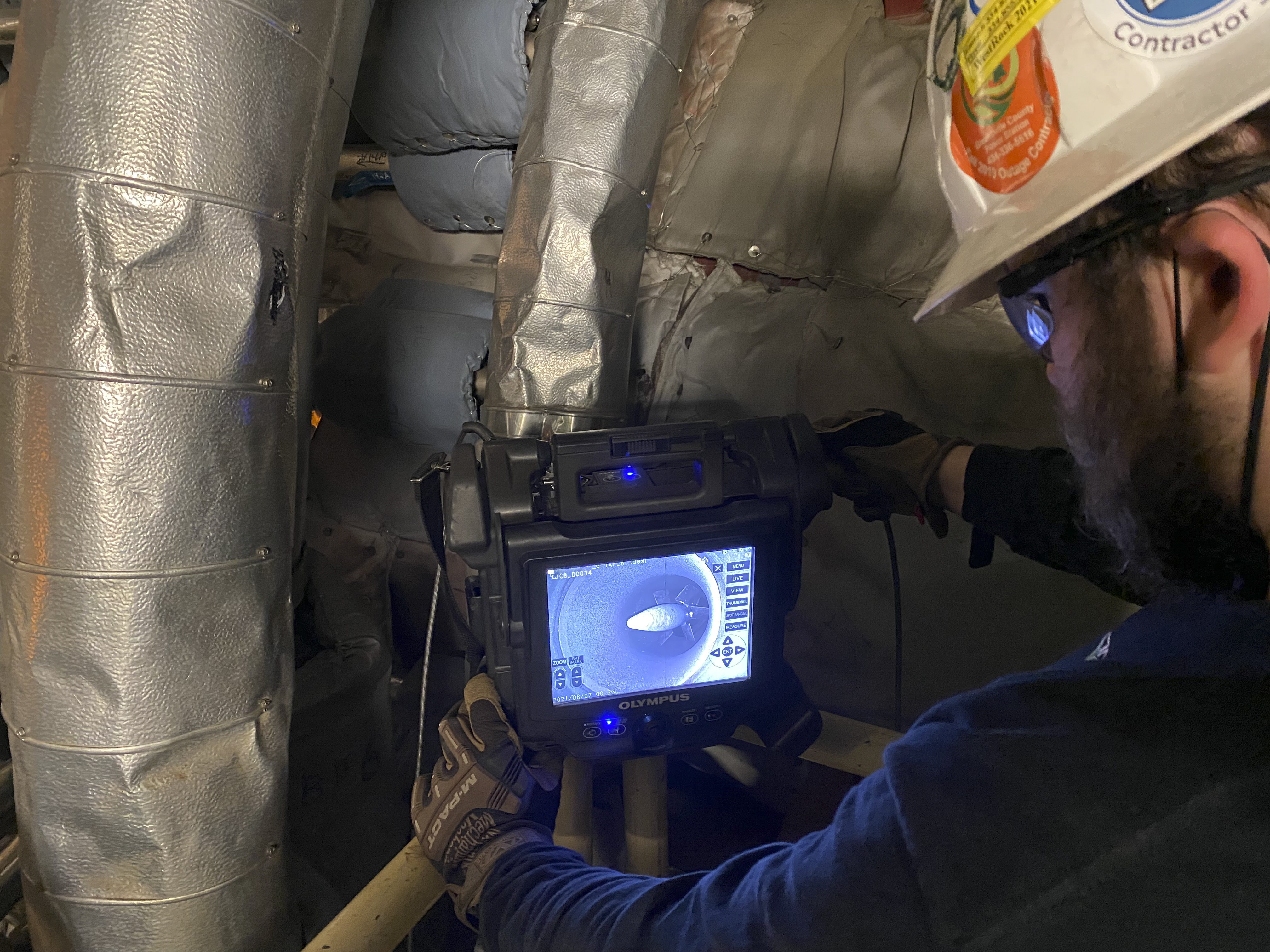 Veracity Technology Solutions inspector using the IPLEX NX videoscope to conduct a borescopic inspection of a gas turbine in a power generation plant