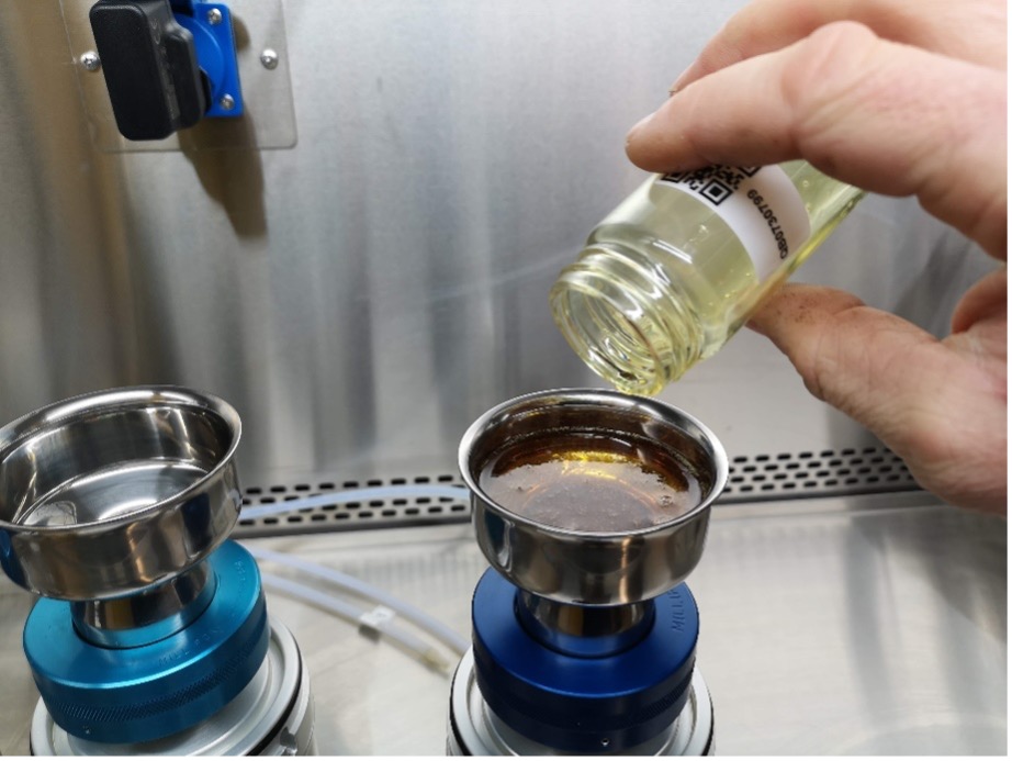 Versamento di un campione d'olio in un imbuto per un'analisi della pulizia tecnica dell'olio