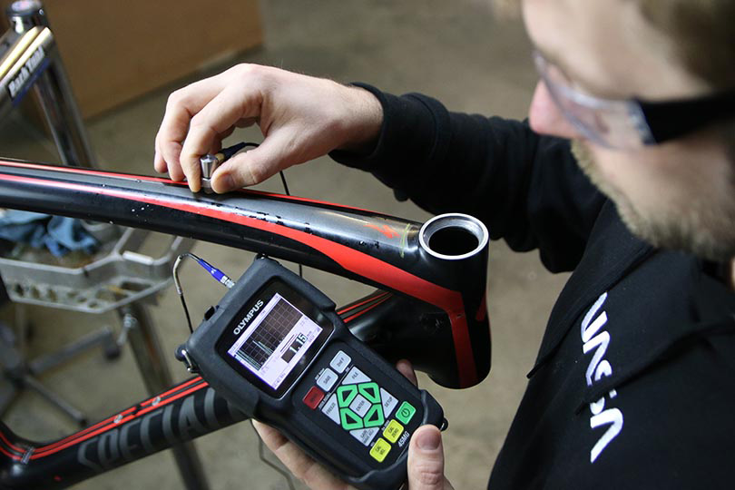 Shawn Small ejecutando una inspección ultrasónica en un cuadro (marco) de una bicicleta de fibra de carbono con un medidor de espesores 45 MG.