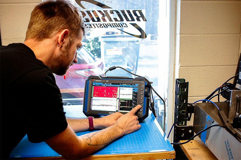 Ruckus Composites' Shawn Small pressing the buttons on an OmniScan X3 phased array ultrasonic testing flaw detector 