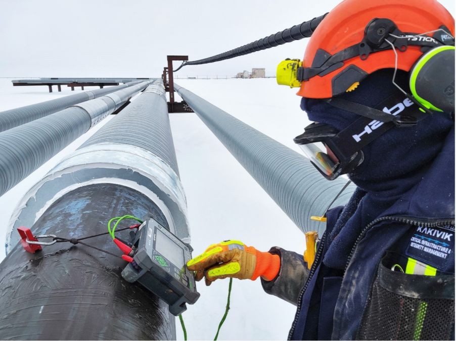 Kakivik Asset Management inspector inspecting a pipeline using Evident ultrasonic inspection technology in snow-covered Alaskan oilfield